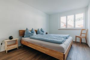 um quarto com uma cama com lençóis azuis e uma janela em Chuenislodge1 Neu, grosse Terrasse & Designerofen, prächtige Aussicht em Adelboden