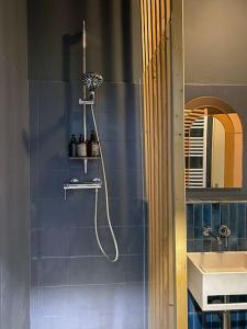 y baño de azulejos azules con ducha y lavamanos. en Apartment im Wein- und Freizeitidyll Klöch en Klöch