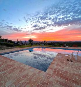 a swimming pool with a sunset in the background at "Villa Bizzi" in Monte Castelli