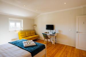 a bedroom with a bed and a yellow couch at Santa Clara Lisbon Rooms in Lisbon
