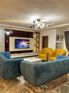 ein Wohnzimmer mit einem blauen Sofa und gelben Stühlen in der Unterkunft 3 Bedroom Luxury Apartment in Lekki in Lagos