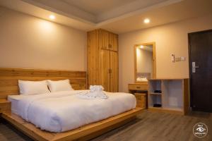 a bedroom with a large white bed and a mirror at Hotel Pokharaeye in Pokhara