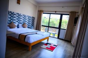 um quarto com uma cama e uma janela grande em Hotel Kaavi em Pokhara