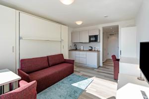 ein Wohnzimmer mit einem roten Sofa und einer Küche in der Unterkunft Huber Living Basic 208 in Germering