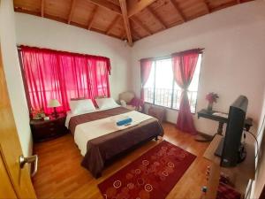 a bedroom with a bed with red curtains and a television at Casa entera - La Campiña Suiza TABIO TENJO in Tenjo