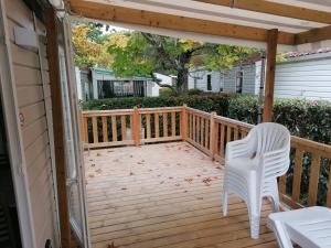 - une terrasse en bois avec 2 chaises blanches dans l'établissement Mobil Home 4-6 personnes, à Gastes