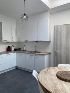 FDS Cosy House في خنت: مطبخ بدولاب بيضاء وطاولة خشبية