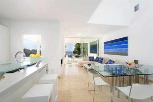 Il dispose d'une cuisine et d'un salon avec une table et des chaises en verre. dans l'établissement Casa Laila - acceso directo al mar, piscina y wifi, à Portopetro