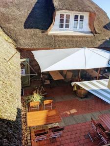 eine Terrasse mit einem Tisch, Stühlen und einem Sonnenschirm in der Unterkunft Tetens Gasthof in Süderlügum