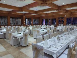 un gran salón de banquetes con mesas y sillas blancas en Hotel Ravni Gaj, en Knić
