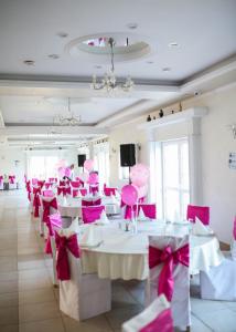 un comedor con mesas rosas y sillas con arcos en Hotel Ravni Gaj, en Knić