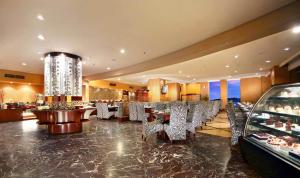 un restaurante con sillas, mesas y una lámpara de araña en ASTON Samarinda Hotel and Convention Center, en Samarinda