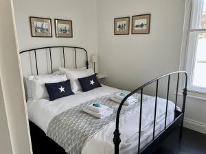 Tasteful apartment moments from the beach, Bunting by Whitstable-Holidays في وايتستابل: غرفة نوم مع سرير ووسائد زرقاء وبيضاء