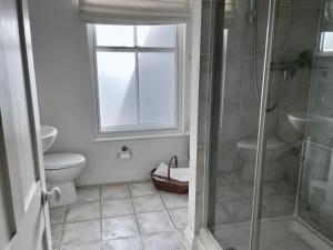ein Bad mit einer Dusche, einem WC und einem Fenster in der Unterkunft Tasteful apartment moments from the beach, Bunting by Whitstable-Holidays in Whitstable