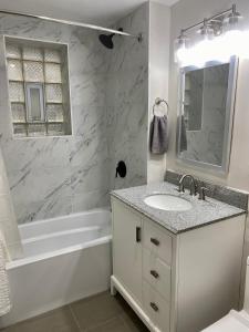 uma casa de banho branca com um lavatório, uma banheira e um espelho. em Lincoln Park Aparment with Backyard! em Chicago