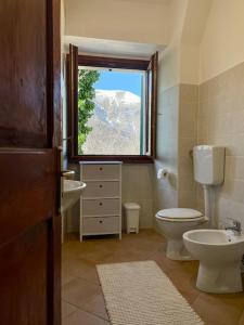 a bathroom with a toilet and a sink and a window at Casa Lola nel centro storico di Bolognola in Pintura di Bolognola