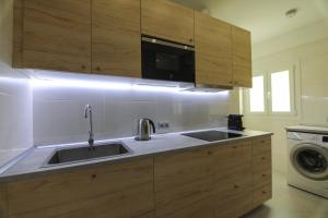 a kitchen with wooden cabinets and a sink at RentalSevilla Moderno apartamento en Triana de 95m2 in Seville