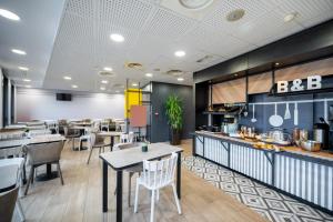 un restaurant avec des tables et des chaises et une cuisine dans l'établissement B&B HOTEL Lille Grand Stade, à Villeneuve d'Ascq