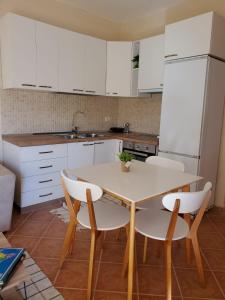cocina con armarios blancos, mesa y sillas en Standart apartment en Durrës