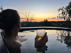 a woman holding a glass of whiskey in a pool at Nature's Loft in Fouriesburg