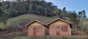 ein kleines Haus mit einem Hügel im Hintergrund in der Unterkunft Pousada Rural e Pesqueiro Chalé da serra in Conceição da Ibitipoca
