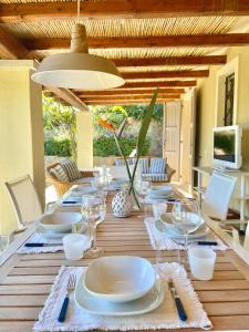 una mesa de comedor con platos y copas de vino. en DOMUS MARIS Villa Charmant Porto Giunco Notteri VILLASIMIUS en Notteri