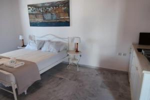 a white bedroom with a bed and a table at SUNSET STUDIO - HYDRA DREAM HOUSES in Hydra