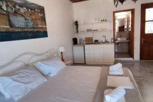 a bedroom with a large white bed and a kitchen at SUNSET STUDIO - HYDRA DREAM HOUSES in Hydra