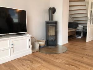 sala de estar con chimenea y TV en Kavelweg Haus JENNY, en Zingst