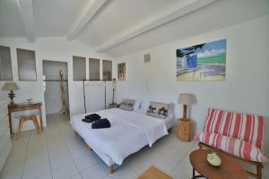 ein weißes Schlafzimmer mit einem Bett und einem Sofa in der Unterkunft Villa Escale en Re in Sainte-Marie-de-Ré