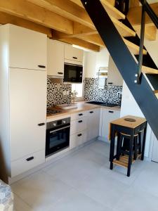 une cuisine avec des placards blancs et une table avec un tabouret dans l'établissement Coquette maison à la campagne, à Apremont