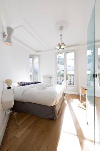 a white bedroom with a large bed and windows at Veeve - By the Palais Royal in Paris