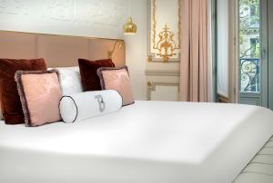 Una cama blanca con almohadas encima. en Hotel Bowmann en París
