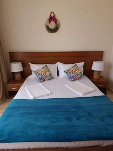 uma cama com um cobertor azul e almofadas em KALIAKRIA RESORT AP. 95 em Topola