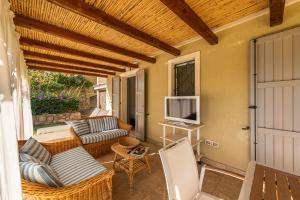 patio con sofá y TV en el porche en DOMUS MARIS Villa Charmant Porto Giunco Notteri VILLASIMIUS, en Notteri
