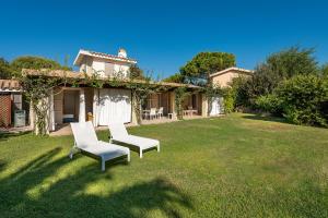 Un patio con dos sillas y una casa. en DOMUS MARIS Villa Charmant Porto Giunco Notteri VILLASIMIUS, en Notteri
