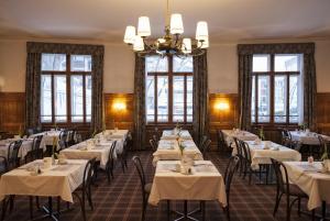 ein Esszimmer mit Tischen und weißen Tischdecken in der Unterkunft Hotel National by Mountain Hotels in Davos