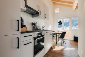 a kitchen with white cabinets and a table at Chuenislodge3 neu&stilvoll, 2Balkone, echtes Bijou mit top-Aussicht in Adelboden