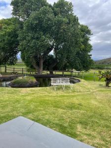 a white bench sitting in the grass under a tree at The Stables in Protem