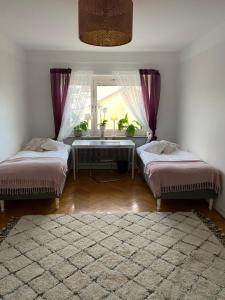 a bedroom with two beds and a window and a table at HoMade B&B, Gamla Stan in Norrköping