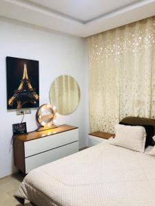- une chambre avec un lit, une commode et la tour Eiffel dans l'établissement S+1 à aouina aux rez-de-chaussée, à Tunis