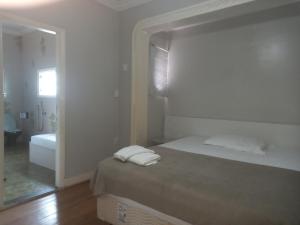 a white bedroom with a bed and a bathroom at Uba Apart imóveis in Ubá