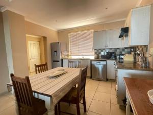 uma cozinha com uma mesa de madeira e cadeiras numa cozinha em VIlla for Family and Golf em Mossel Bay