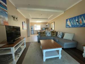 ein Wohnzimmer mit einem Sofa und einem TV in der Unterkunft VIlla for Family and Golf in Mossel Bay