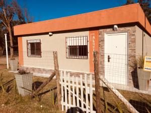 una pequeña casa con una puerta blanca y una valla en Alquimia, en Sauce de Portezuelo