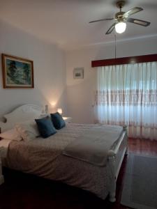 Schlafzimmer mit einem Bett mit blauen Kissen und einem Deckenventilator in der Unterkunft Casa Branca in Lagoa