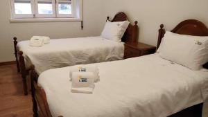 2 camas en una habitación con sábanas blancas en Albergue de São Bento en Caminha