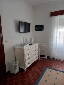 a bedroom with a dresser with a tv on the wall at Casa Branca in Lagoa