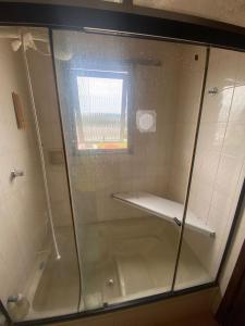 a shower with a glass door in a bathroom at Apt grande no centro de São Lourenço perto de tudo in São Lourenço