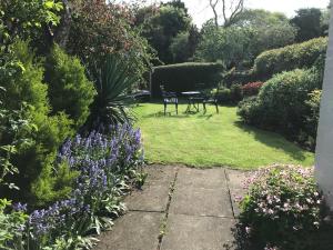 un jardín con 2 sillas y flores púrpuras en Idyllic Stratford upon Avon cottage en Shottery